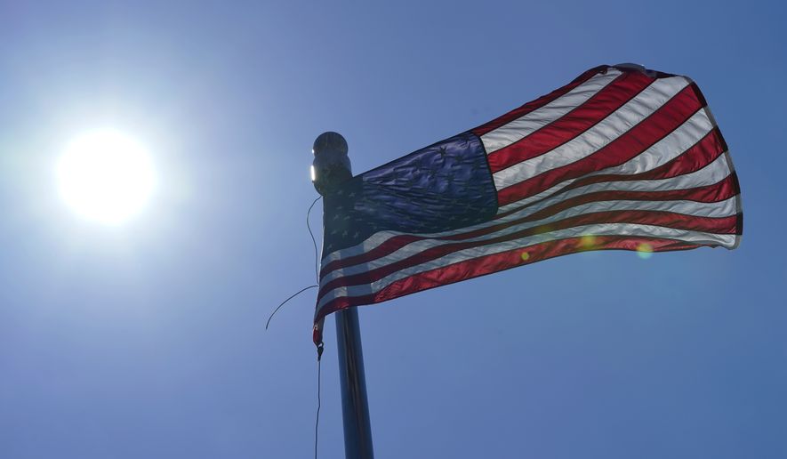 A U.S. flag flies with the sun in the background, Wednesday, June 30, 2021, in downtown Seattle. Temperatures cooled considerably in western Washington, Oregon and British Columbia Wednesday after several days of record-breaking heat, but the interior regions of the region were still sweating through triple-digit temperatures as the weather system moved east. (AP Photo/Ted S. Warren)