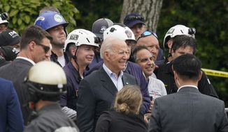 U.S. President Joe Biden, center, poses for a photo with search and rescue workers after visiting a makeshift memorial to the scores of victims of the partial collapse at the Champlain Towers South condo building, Thursday, July 1, 2021, in Surfside, Fla. President Biden drew on his own experiences with grief and loss to comfort families affected by the Florida condo collapse, telling them to &quot;never give up hope&quot; even as the search for survivors paused early Thursday, a week after the building came down.(AP Photo/Gerald Herbert)