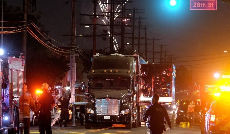 Fireworks continue to fill the skyline as emergency personnel respond to the explosion of an armored Los Angeles Police Department tractor-trailer in South Los Angeles Wednesday evening, June 30, 2021. A cache of illegal fireworks seized at a South Los Angeles home exploded, damaging nearby homes and cars and causing injuries, authorities said. (AP Photo/Ringo H.W. Chiu)