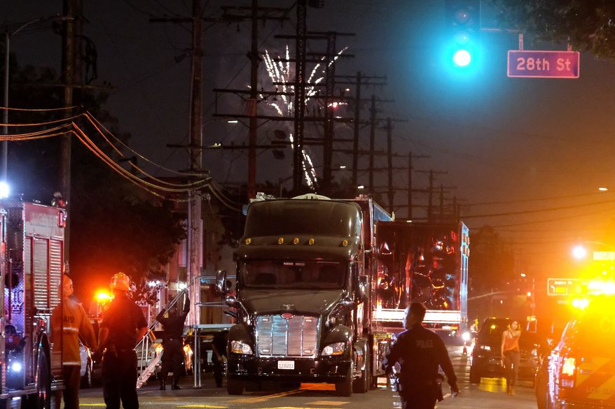 Fireworks continue to fill the skyline as emergency personnel respond to the explosion of an armored Los Angeles Police Department tractor-trailer in South Los Angeles Wednesday evening, June 30, 2021. A cache of illegal fireworks seized at a South Los Angeles home exploded, damaging nearby homes and cars and causing injuries, authorities said. (AP Photo/Ringo H.W. Chiu)