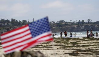 People walk along La Jolla Shores beach as Independence Day weekend nears, Thursday, July 1, 2021, in San Diego. Holiday travel over the Independence Day weekend is expected to nearly return to pre-pandemic levels, according to AAA. (AP Photo/Gregory Bull)