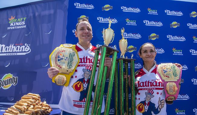 Winners Joey Chestnut and Michelle Lesco pose with their championship belts and trophies at the Nathan's Famous Fourth of July International Hot Dog-Eating Contest in Coney Island's Maimonides Park on Sunday, July 4, 2021, in Brooklyn, New York. (AP Photo/Brittainy Newman)