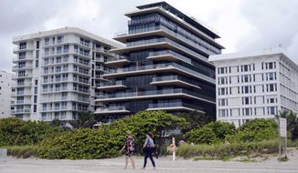 Beachgoers walk by the beach entrance to the Arte by Antonio Citterio condominium, center, Tuesday, June 29, 2021, in Surfside, Fla. Jared Kushner and Ivanka Trump rent an apartment at Arte while their home is under construction at nearby Indian Creek Village. (AP Photo/Marta Lavandier)