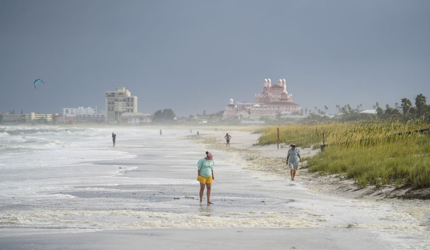 Beach walkers walk along the sand on Pass-a-Grille the morning after Tropical Storm Elsa moved over the Tampa Bay Area, Wednesday, July 7, 2021 in St. Pete Beach, Fla.  (Martha Asencio-Rhine/Tampa Bay Times via AP)