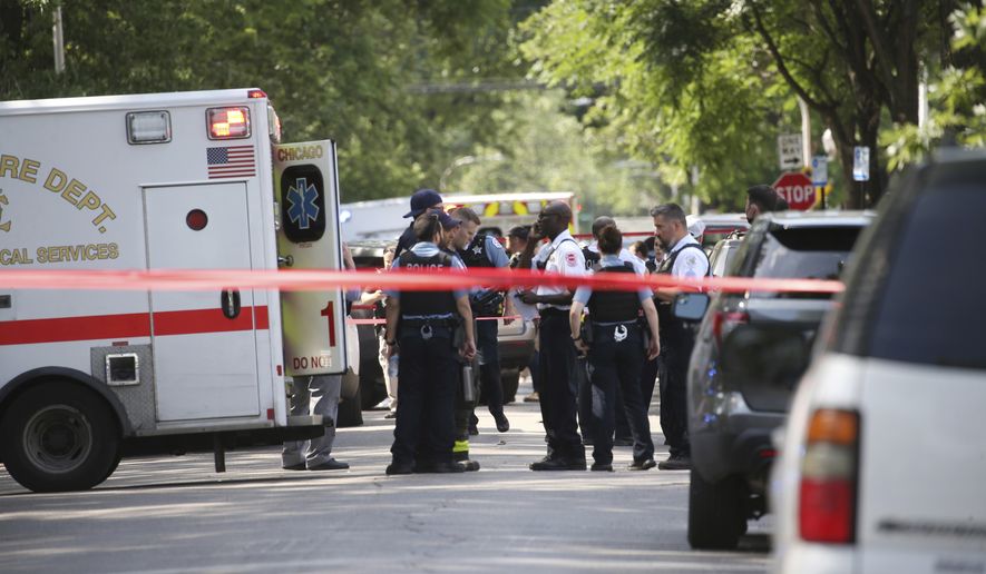 Chicago police and emergency medical personnel work at the scene of a police-involved shooting in Chicago, Friday, July 9, 2021. Law enforcement officers in Chicago shot and wounded a 33-year-old man who pointed a gun at them as they tried to arrest him Friday, authorities said. (Antonio Perez/Chicago Tribune via AP)