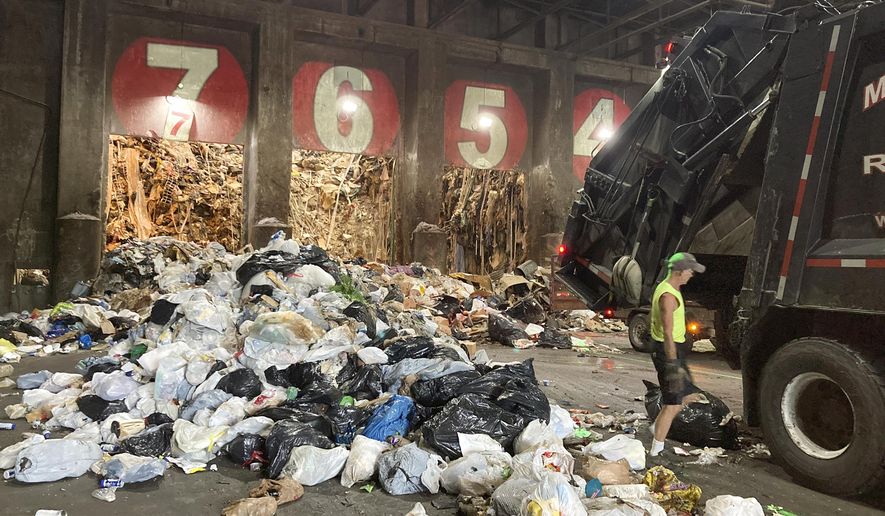 A worker unloads a garbage truck at ecomaine, Tuesday, June 22, 2021, in Portland, Maine. Waste-to-energy converters like ecomaine are seeing an uptick in the amount of trash they collect to produce power as the coronavirus pandemic winds down in the U.S. These facilities burn garbage to create electricity. Environmentalists and renewable energy advocates are debating whether creating more energy by burning the excess waste is a safe idea. (AP Photo/Patrick Whittle)