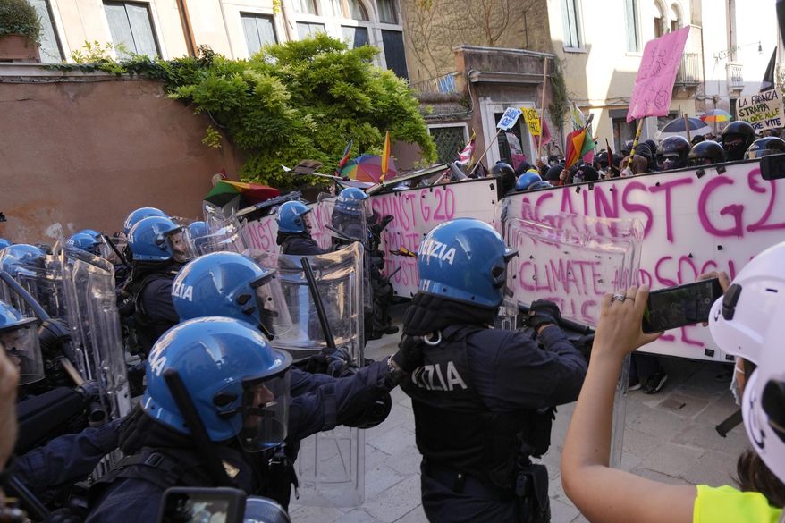 Italian Policemen in riot gears clash with demonstrators during a protest against the G20 Economy and Finance ministers and Central bank governors&#x27; meeting in Venice, Italy, Saturday, July 10, 2021. (AP Photo/Luca Bruno)