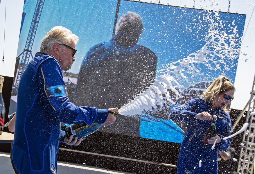 Virgin Galactic founder Richard Branson, left, sprays champagne to crew member Beth Moses while celebrating their flight to space from Spaceport America near Truth or Consequences, N.M., Sunday, July 11, 2021. (AP Photo/Andres Leighton)
