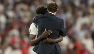 England&#39;s manager Gareth Southgate embraces Bukayo Saka after he failed to score a penalty during a penalty shootout after extra time during of the Euro 2020 soccer championship final match between England and Italy at Wembley stadium in London, Sunday, July 11, 2021. (Carl Recine/Pool Photo via AP)