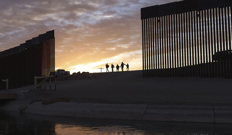 In this Thursday, June 10, 2021, photo, a pair of migrant families from Brazil pass through a gap in the border wall to reach the United States after crossing from Mexico to Yuma, Ariz., to seek asylum.  (AP Photo/Eugene Garcia) **FILE**