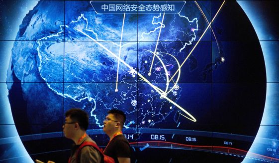 In this Sept. 12, 2017, file photo, attendees walk past an electronic display showing recent cyberattacks in China at the China Internet Security Conference in Beijing. Tech experts in China who find a weakness in computer security would be required to tell the government instead of publicizing it under rules announced Tuesday, July 13, 2021, as part of the ruling Communist Party’s sweeping effort to tighten control over information. (AP Photo/Mark Schiefelbein, File)