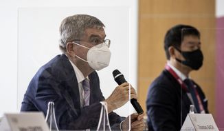 IOC President Thomas Bach, left, speaks to Tokyo 2020 President Seiko Hashimoto, not in photo, during their meeting at the Tokyo 2020 Headquarters Tuesday, July 13, 2021 in Tokyo, Japan. Bach appeared in public on Tuesday for the first time since arriving in Tokyo last week with the pandemic-postponed Olympics opening in just 10 days.  (Takashi Aoyama/Pool Photo via AP)