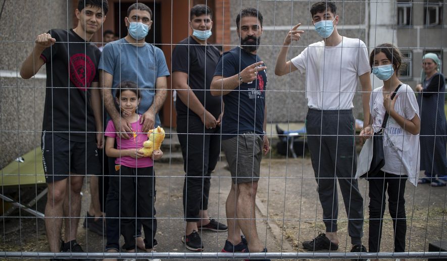 Migrants from Iraq speak to journalists through a fence at the refugee camp in the village of Verebiejai, some 145km (99,1 miles) south from Vilnius, Lithuania, Sunday, July 11, 2021. Migrants at the school in the village of Verebiejai, about 140 kilometers (87 miles) from Vilnius, haven&#x27;t been allowed to leave the premises and are under close police surveillance. Some have tested positive for COVID-19 and have been isolated in the building. (AP Photo/Mindaugas Kulbis)