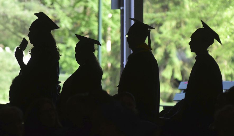 In this Friday, June 1, 2018,, file photo, graduates are silhouetted against the green landscape as they line up to receive their diplomas at Berkshire Community College&#39;s commencement exercises at the Shed at Tanglewood in Lenox, Mass. Critics of traditional four-year degree programs say grads leave burdened with student loans and no clear path to a career. But experts say the four-year degree is still a good investment since it leads to higher overall lifetime earnings compared to workers without a degree. (Gillian Jones/The Berkshire Eagle via AP, File)