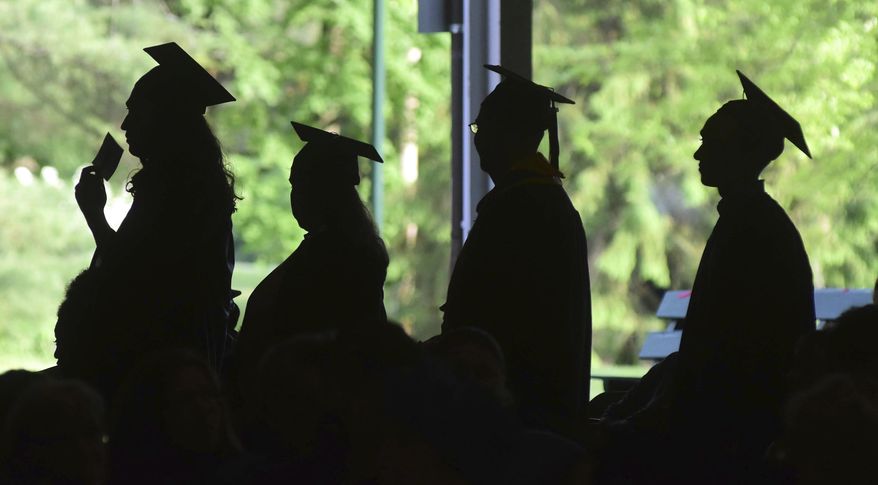 In this Friday, June 1, 2018,, file photo, graduates are silhouetted against the green landscape as they line up to receive their diplomas at Berkshire Community College&#39;s commencement exercises at the Shed at Tanglewood in Lenox, Mass. Critics of traditional four-year degree programs say grads leave burdened with student loans and no clear path to a career. But experts say the four-year degree is still a good investment since it leads to higher overall lifetime earnings compared to workers without a degree. (Gillian Jones/The Berkshire Eagle via AP, File)