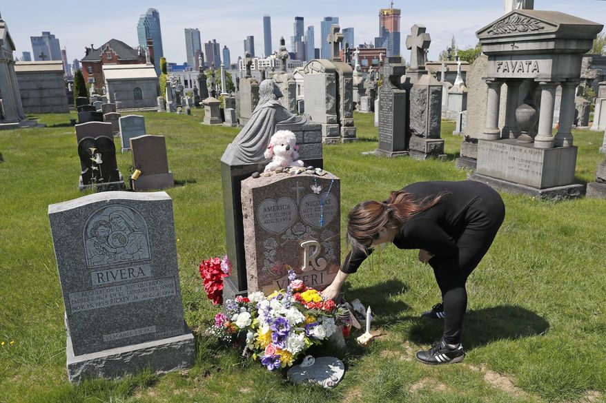 In this Sunday, May 10, 2020, file photo, Sharon Rivera adjusts flowers and other items left at the grave of her daughter, Victoria, at Calvary Cemetery in New York, on Mother&#x27;s Day. Victoria died of a drug overdose on Sept. 22, 2019, when she just 21 years old. According to a report released by the Centers for Disease Control and Prevention on Wednesday, July 14, 2021, drug overdose deaths soared to a record 93,000 last year in the midst of the COVID-19 pandemic. (AP Photo/Kathy Willens, File)