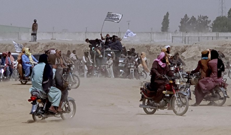 Supporters of the Taliban carry the Taliban&#39;s signature white flags in the Afghan-Pakistan border town of Chaman, Pakistan, Wednesday, July 14, 2021. The Taliban are pressing on with their surge in Afghanistan, saying Wednesday that they seized Spin Boldaka, a strategic border crossing with Pakistan — the latest in a series of key border post to come under their control in recent weeks. (AP Photo/Tariq Achkzai)