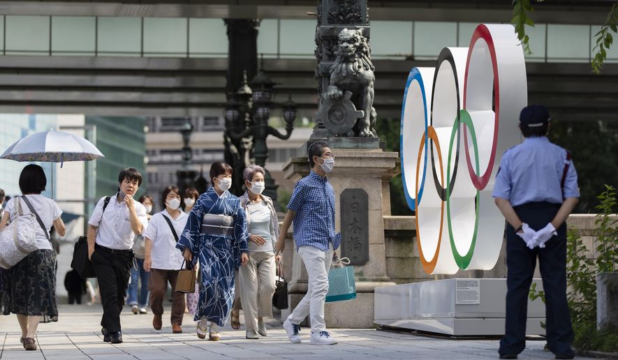 People walk by the Olympic rings installed by the Nippon Bashi bridge in Tokyo on Thursday, July 15, 2021. (AP Photo/Hiro Komae)