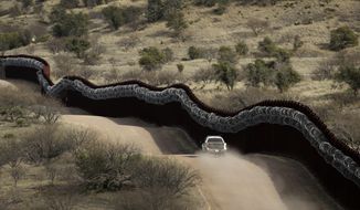In this March 2, 2019, file photo, a Customs and Border Control agent patrols on the U.S. side of a razor-wire-covered border wall along the Mexico east of Nogales, Ariz. (AP Photo/Charlie Riedel, File)
