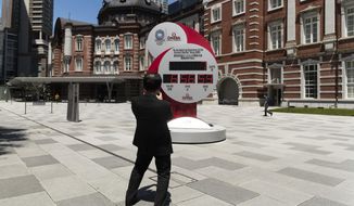 A man takes a picture of a countdown clock that shows seven more days to go before the opening ceremony of the Tokyo Olympic Games in Tokyo Friday, July 16, 2021. (AP Photo/Hiro Komae)