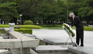 International Olympic Committee President Thomas Bach offers flowers to Hiroshima Memorial Cenotaph during his visit Friday, July 16, 2021, in Hiroshima, western Japan. (AP Photo/Eugene Hoshiko, Pool)