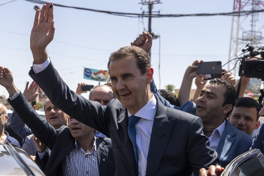 FILE - In this May 26, 2021, file photo, Syrian President Bashar Assad, center, waves to his supporters at a polling station during the Presidential elections in the town of Douma, in the eastern Ghouta region, near the Syrian capital Damascus, Syria. President Assad was sworn in Saturday, July 17,  for a fourth seven-year term in the war-torn country.(AP Photo/Hassan Ammar, File)