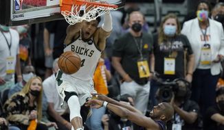 Milwaukee Bucks forward Giannis Antetokounmpo, top, dunks over Phoenix Suns guard Chris Paul during the second half of Game 5 of basketball&#x27;s NBA Finals, Saturday, July 17, 2021, in Phoenix. (AP Photo/Ross D. Franklin)