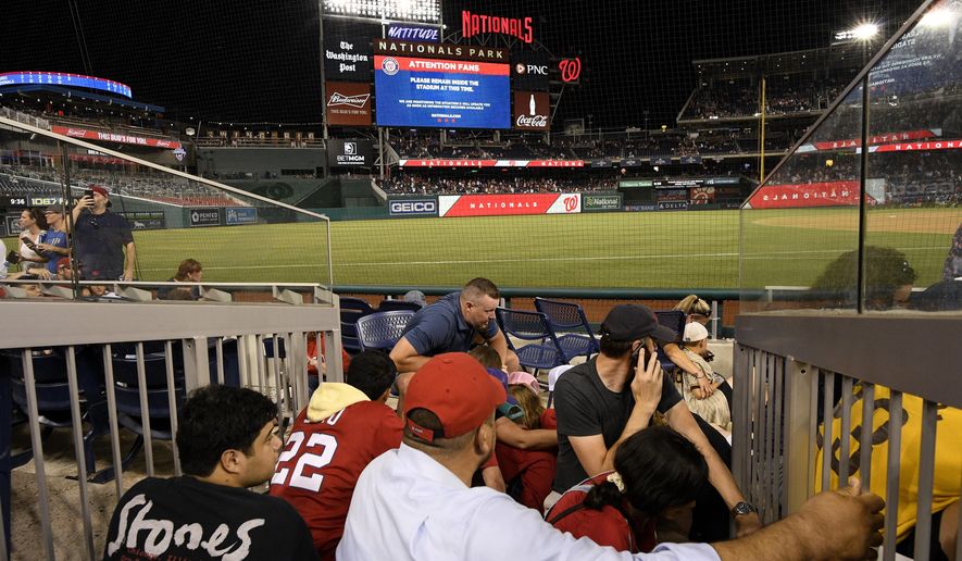 Spectators take cover during a stoppage in play due to an incident near the ballpark during the sixth inning of a baseball game between the Washington Nationals and the San Diego Padres, Saturday, July 17, 2021, in Washington. (AP Photo/Nick Wass)