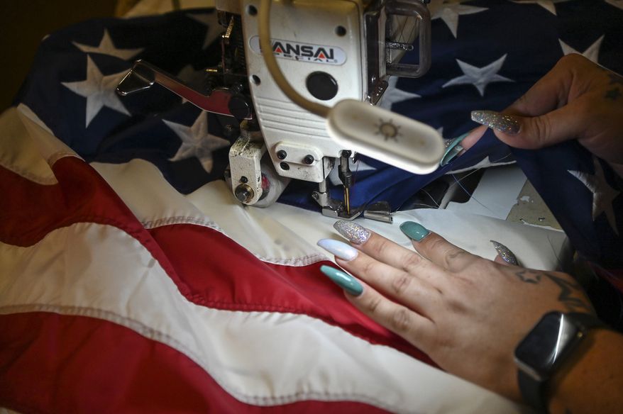 A supervisor sews the stars to finish the assembly of the American flag at North American Manufacturing on June 28, 2021, in Scranton, Pa. Since 2016, the staff at North American Manufacturing on Barring Avenue has meticulously produced about 8,000 full-size American flags each year, which are sold to the Defense Logistics Agency and awarded to government retirees. (Jason Farmer/The Times-Tribune via AP) ** FILE **