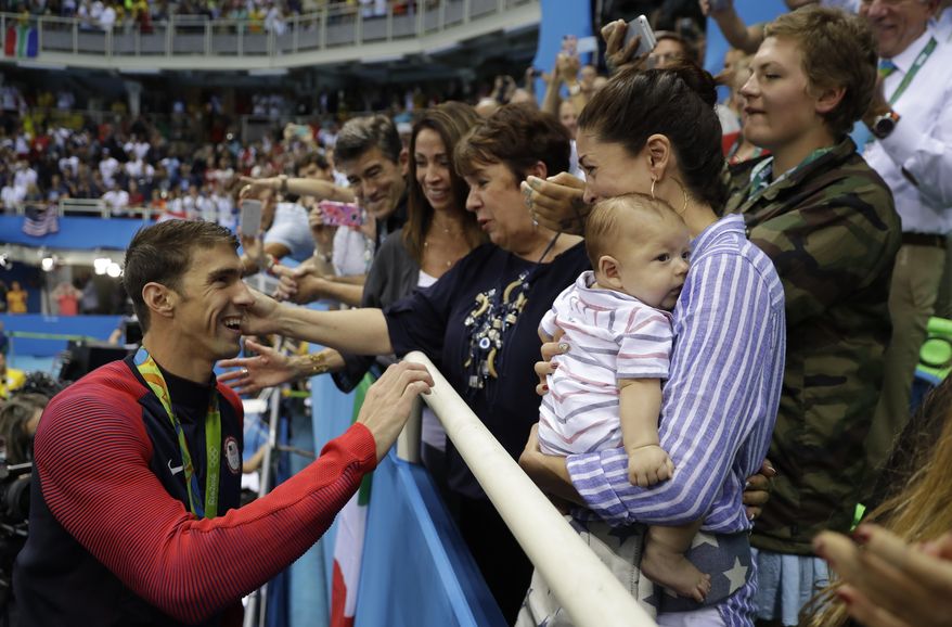 United States&#39; Michael Phelps celebrates winning his gold medal in the men&#39;s 200-meter butterfly with his mother Debbie, fiance Nicole Johnson and baby Boomer during the swimming competitions at the 2016 Summer Olympics in Rio de Janeiro, Brazil. (AP Photo/Matt Slocum, File)