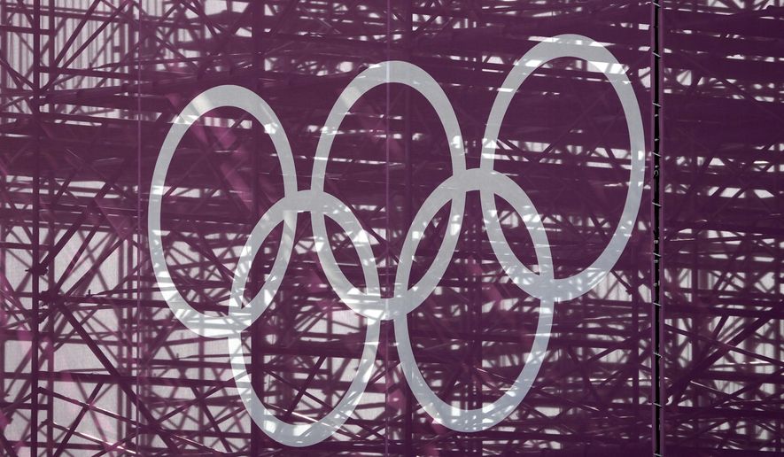 The Olympic rings are set against a lattice work of pipes supporting a grandstand at the skateboarding arena for the 2020 Summer Olympics, Tuesday, July 20, 2021, at the Ariake Urban Sports Park in Tokyo. The pandemic-delayed games open on July 23 without spectators at most venues. (AP Photo/Charlie Riedel)