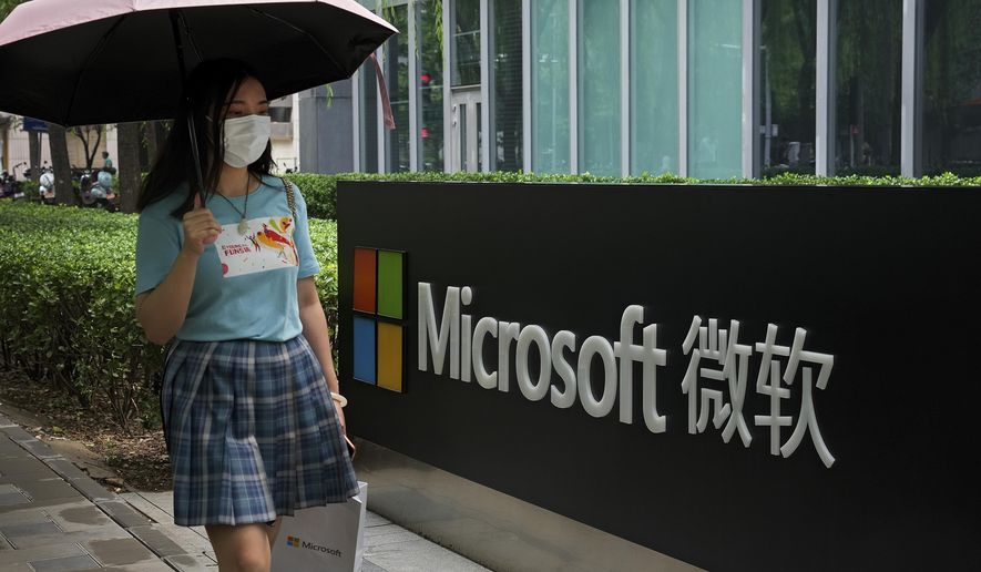 A woman wearing a face mask to help curb the spread of the coronavirus walks by the Microsoft office building in Beijing, Tuesday, July 20, 2021. The Biden administration and Western allies formally blamed China on Monday for a massive hack of Microsoft Exchange email server software and asserted that criminal hackers associated with the Chinese government have carried out ransomware and other illicit cyber operations. (AP Photo/Andy Wong)