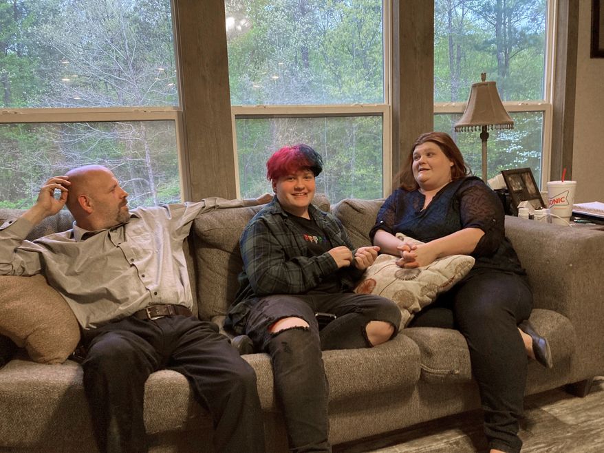FILE - In this April 15, 2021 file photo, Andrew Bostad, center, talks with his mother, Brandi Evans and stepdad Jimmy Evans at their home in Bauxite, Ark. Andrew is one of hundreds of transgender youth in Arkansas who could have their hormone therapy cut off under a new state law banning gender confirming treatments for minors.    A federal judge on Wednesday, July 21, has temporarily blocked Arkansas&#39; ban on gender confirming treatments for transgender youth while a lawsuit challenging the prohibition proceeds.    (AP Photo/Andrew DeMillo, File)