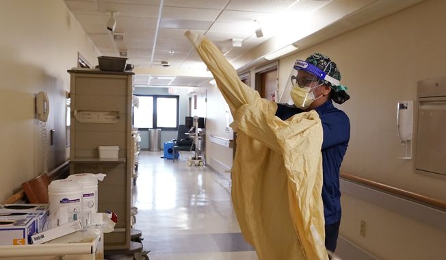 In this April 21, 2021, file photo, a registered dons protective gear before entering a room at a hospital in Royal Oak, Mich. In 2021, U.S. hospitalizations and deaths are nearly all among the unvaccinated, and real-world data from Britain and Israel support that protection against the worst cases remains strong. What scientists call breakthrough infections in people who are fully vaccinated make up a small fraction of cases. (AP Photo/Carlos Osorio) ** FILE **