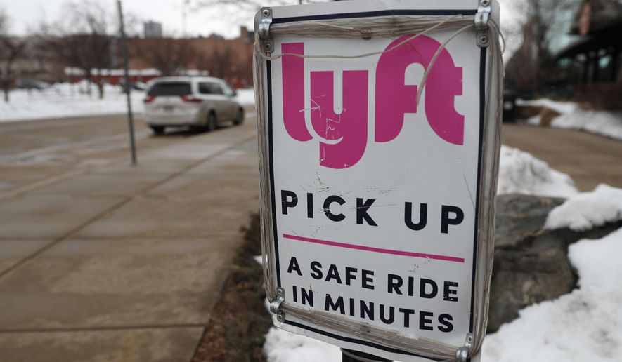In this Wednesday, Feb. 12, 2020, photo, a sign marks the pick lane for Lyft car share service outside the Pepsi Center in downtown Denver.  Ford Motor Co. and a self-driving vehicle company it partly owns will join with the Lyft ride-hailing service to offer autonomous rides on the Lyft network. The service using Ford vehicles and a driving system developed by Argo AI will begin in Miami later this year and start in Austin, Texas, in 2022.  (AP Photo/David Zalubowski)