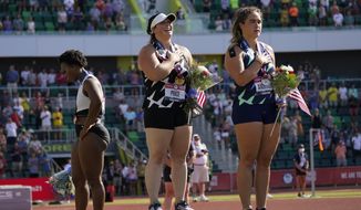 In this June 26, 2021, file photo, Gwendolyn Berry, left, looks away as DeAnna Price and Brooke Andersen stand for the national anthem after the finals of the women&#39;s hammer throw at the U.S. Olympic Track and Field Trials in Eugene, Ore.  (AP Photo/Charlie Riedel, File)  **FILE**