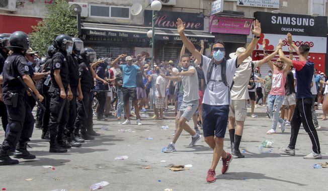 Protesters face Tunisian police officers during a demonstration in Tunis, Tunisia, Sunday, July 25, 2021. Violent demonstrations broke out on Sunday in several Tunisian cities as protesters expressed anger at the deterioration of the country&#x27;s health, economic and social situation. (AP Photo/Hassene Dridi)