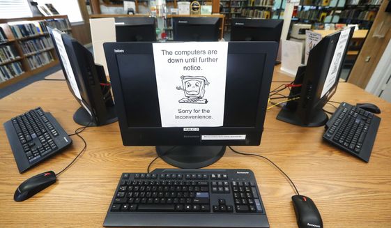 In this Aug. 22, 2019, photo, signs on a bank of computers tell visitors that the machines are not working at the public library in Wilmer, Texas. The Associated Press has learned new details about a ransomware attack that affected roughly two dozen Texas communities two years ago. Thousands of pages obtained by AP and interviews with people involved show Texas communities struggled for days with disruptions to core government services as workers in small cities and towns endured a cascade of frustrations brought on by the sophisticated cyberattack. (AP Photo/Tony Gutierrez) **FILE**