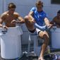Argentina&#39;s Santiago Mare, center, takes off his sock as Marcos Moneta, left, and fellow teammates soak in ice baths following men&#39;s rugby sevens team practice in the midday heat at the Tokyo 2020 Olympics, in Tokyo, Friday, July 23, 2021. (AP Photo/David Goldman)