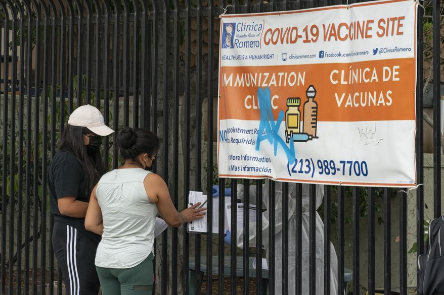 Immigrants fill out forms before getting vaccinated at the Clínica Monseñor Oscar A. Romero in the Pico-Union district of Los Angeles, Monday, July 26, 2021. The clinic is a COVID-19 vaccine site. California said it will require proof of vaccination or weekly testing for all state workers and millions of public- and private-sector health care employees starting in August. (AP Photo/Damian Dovarganes) **FILE**