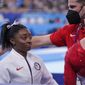 Coach Laurent Landi comforts Simone Biles, of the United States, after she exited the team final with apparent injury, at the 2020 Summer Olympics, Tuesday, July 27, 2021, in Tokyo. The 24-year-old reigning Olympic gymnastics champion Biles huddled with a trainer after landing her vault. She then exited the competition floor with the team doctor. (AP Photo/Gregory Bull)