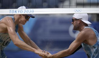 Tri Bourne, left, of the United States, celebrates with teammate Jacob Gibb, after winning a men&#39;s beach volleyball match against Switzerland at the 2020 Summer Olympics, Wednesday, July 28, 2021, in Tokyo, Japan. (AP Photo/Felipe Dana)