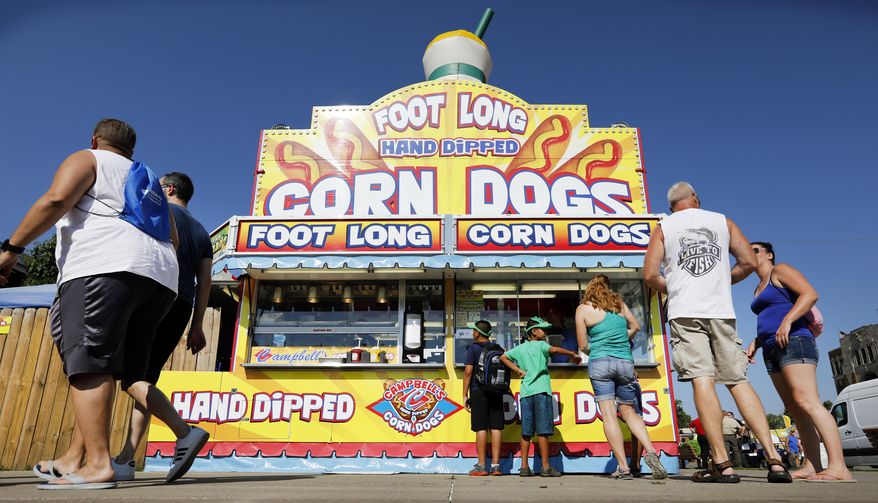 In this Aug. 9, 2018 file photo, Iowa State fairgoers line up to get a corn dog at a concession stand during the opening day of the Iowa State Fair in Des Moines, Iowa. (AP Photo/Charlie Neibergall, File)