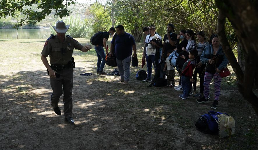 In this June 16, 2021 file photo, Texas Department of Public Safety officers work with a group of migrants who crossed the border and turned themselves in Del Rio, Texas. (AP Photo/Eric Gay, File)  **FILE**