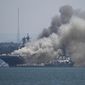 In this July 12, 2020, file photo, smoke rises from the USS Bonhomme Richard at Naval Base San Diego in San Diego after an explosion and fire. The U.S. Navy said Thursday, July 29, 2021, that charges have been filed against a sailor who is accused of starting a fire last year that destroyed a warship docked off San Diego. The amphibious assault ship called the USS Bonhomme Richard burned for more than four days and was the Navy&#39;s worst U.S. warship fire outside of combat in recent memory. (AP Photo/Denis Poroy, File)  **FILE**