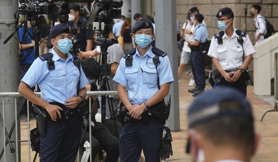 Police officers stand guard outside a court Friday, July 30, 2021, in Hong Kong, as a pro-democracy demonstrator Tong Ying-kit exits the court after his sentencing for the violation of a security law during a 2020 protest. Tong has been sentenced to nine years in prison in the closely watched first case under Hong Kong&#39;s national security law as Beijing tightens control over the territory. (AP Photo/Vincent Yu)