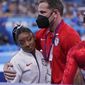Coach Laurent Landi embraces Simone Biles, after she exited the team final with apparent injury, at the 2020 Summer Olympics, Tuesday, July 27, 2021, in Tokyo. The 24-year-old reigning Olympic gymnastics champion Biles huddled with a trainer after landing her vault. She then exited the competition floor with the team doctor. (AP Photo/Gregory Bull)