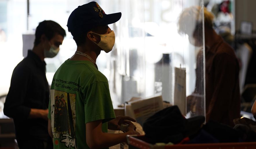 In this July 19, 2021, photo, employees check out customers at 2nd Street second hand store in the Fairfax district of Los Angeles.  New evidence showing the delta variant is as contagious as chickenpox has prompted U.S. health officials to consider changing advice on how the nation fights the coronavirus. Recommending masks for everyone and requiring vaccines for doctors and other health care providers are among measures the Centers for Disease Control and Prevention is considering, Friday, July 30. (AP Photo/Marcio Jose Sanchez) **FILE**