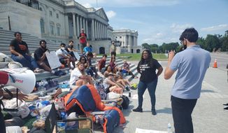 Rep. Cori Bush, Missouri Democrat, is seen at right in black, with a group of progressive protesters on the steps of the U.S. Capitol. Ms. Bush is protesting her House colleagues going on August recess as the federal eviction moratorium expires. She is urging House leadership to return to the Hill to pass an extension on the moratorium. (Photo by Kery Murakami/The Washington Times)