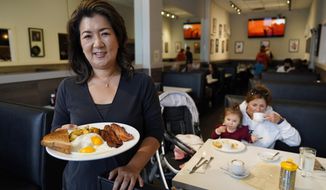 Jeannie Kim holds her popular bacon and eggs breakfast at her restaurant in San Francisco on Friday, July 30, 2021. Thanks to a reworked menu and long hours, Jeannie Kim managed to keep her San Francisco restaurant alive during the coronavirus pandemic. That makes it all the more frustrating that she fears her breakfast-focused diner could be ruined within months by new rules that could make one of her top menu items — bacon — hard to get in California. (AP Photo/Eric Risberg)
